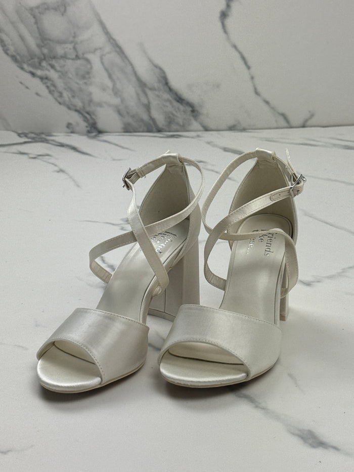 WearMeAgain Friends Like These ivory satin bridal sandals with block heels and crossover straps on marble surface